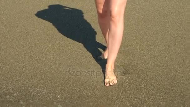 Zpomalené Detailní záběr: Mladá žena s dlouhýma nohama, chůze po pláži a postřik mořské vody do kamery. 4k — Stock video