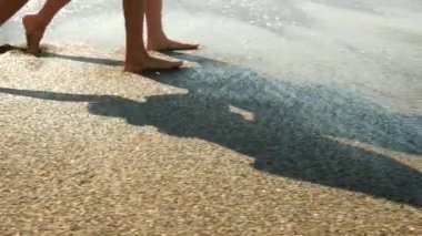 Anne ve kızı sahil, ayakları yavaş hareketleri üzerinde su sıçramalarına yürü. Dalga o kim yürümek bacaklar kapatır. 4k