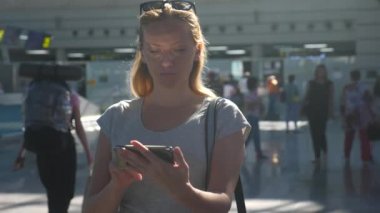 Kadın bir smartphone Havaalanı lounge bekleyen kullanır. Havaalanında uçuş beklentilerini. 4k, ağır çekim