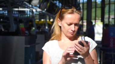 Kadın bir smartphone Havaalanı lounge bekleyen kullanır. Havaalanında uçuş beklentilerini. 4k, ağır çekim