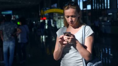 Kadın bir smartphone Havaalanı lounge bekleyen kullanır. Havaalanında uçuş beklentilerini. 4k, ağır çekim