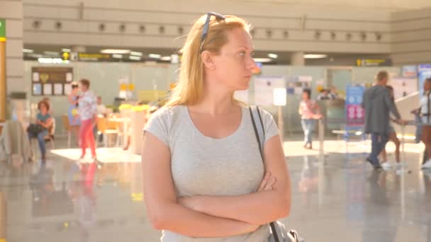 Mujer en la sala de espera del aeropuerto. Expectativas de vuelo en el aeropuerto. 4k, cámara lenta, la chica en el aeropuerto mira el tablero de información . — Vídeo de stock