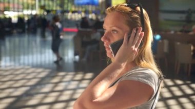 Kadın bir smartphone Havaalanı lounge bekleyen kullanır. Havaalanında uçuş beklentilerini. 4k, ağır çekim
