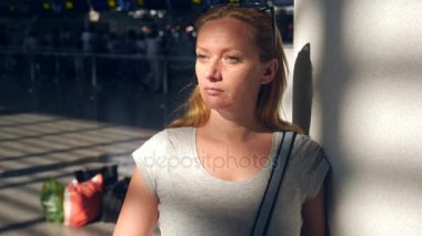 Kadın Havaalanı bekleme salonunda. Havaalanında uçuş beklentilerini. 4k, ağır çekim, bilgi yönetim kurulu Havaalanı bakar kıza.