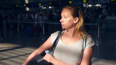 Kadın Havaalanı bekleme salonunda. Havaalanında uçuş beklentilerini. 4k, ağır çekim, bilgi yönetim kurulu Havaalanı bakar kıza.