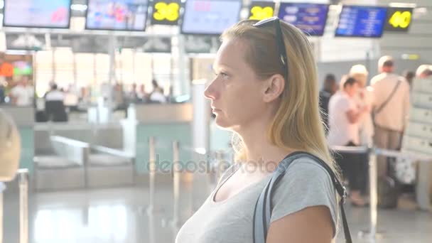 Žena v letištní hale čeká. Očekávání letu na letišti. 4k, Zpomalený pohyb, dívka na letiště vypadá na informační tabuli. — Stock video
