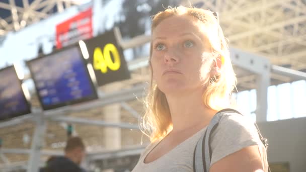 Femme dans le salon d'attente de l'aéroport. Attentes de vol à l'aéroport. 4k, ralenti, La fille à l'aéroport regarde le panneau d'information . — Video
