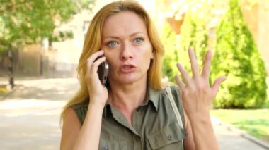 Sarışın konuşuyor küfür ve bağırarak, yaz, şehirde telefonla kamera hareket kızgındır. 4 k. ağır çekim