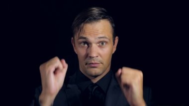 siyah bir arka plan üzerinde siyah giysili bir adam süper yakın çekim. 4 k. ağır çekim. başparmak adam ortaya çıktı. Süper oturum