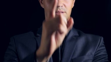 siyah bir arka plan üzerinde siyah giysili bir adam süper yakın çekim. 4 k. ağır çekim. adam puan parmak kamera.
