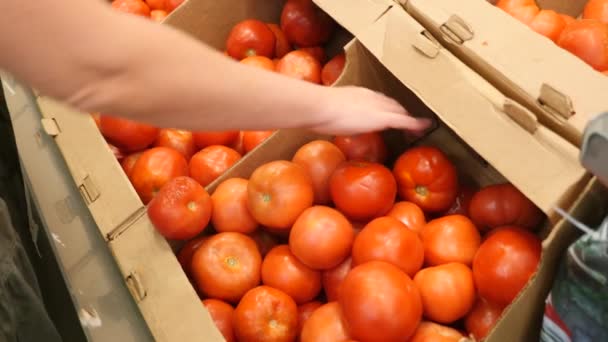 Жінка в супермаркеті на овочевій полиці купує овочі та фрукти. Чоловік вибирає помідори з гнилих овочів. Повільний рух, 4k — стокове відео