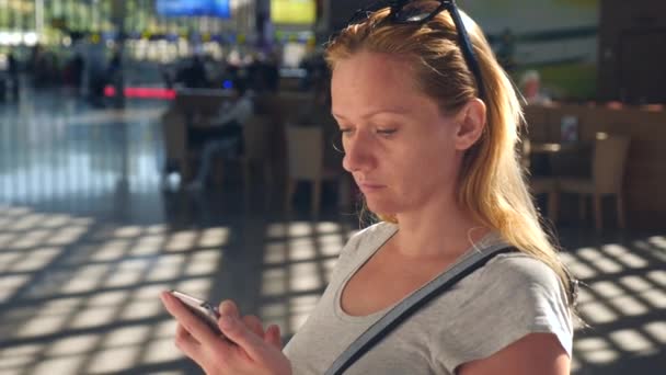 Femme utilise un smartphone dans le salon d'attente de l'aéroport. Attentes de vol à l'aéroport. 4k, au ralenti — Video