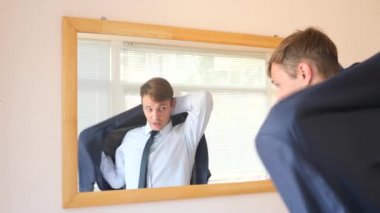 Neşeli bir sevimli adam gülümser ve bir ayna önünde onun yansıması Giydir. 4k, ağır çekim