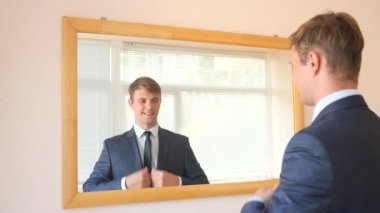 Neşeli bir sevimli adam gülümser ve bir ayna önünde onun yansıması Giydir. 4k, ağır çekim. bir gülümseme provası