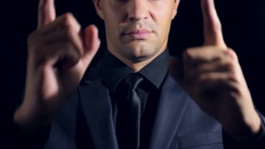 siyah bir arka plan üzerinde siyah giysili bir adam süper yakın çekim. 4 k. ağır çekim. adam puan parmak kamera.
