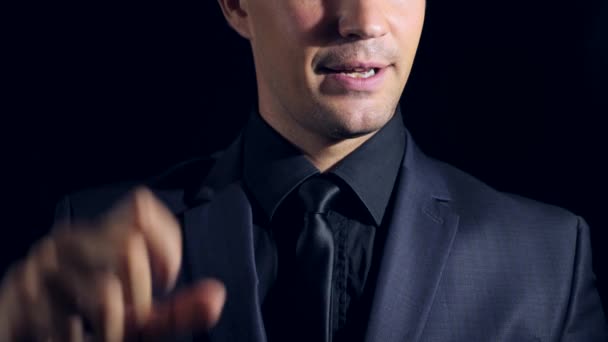Super close-up van een man in de zwarte kleding op een zwarte achtergrond. 4 k. Slow-motion. man geeft zijn handen de grootte van iets — Stockvideo