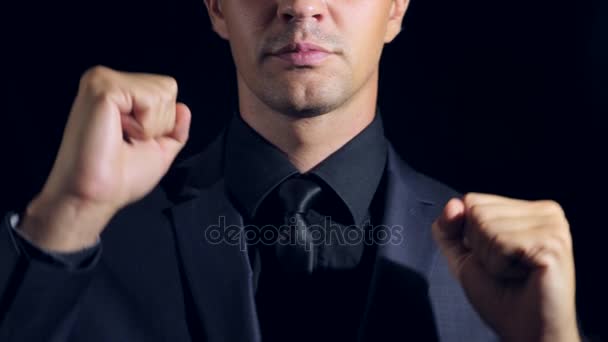 Super close-up de um homem de roupas pretas em um fundo preto. 4K. Movimento lento. homem dança e aponta um dedo para a câmera — Vídeo de Stock