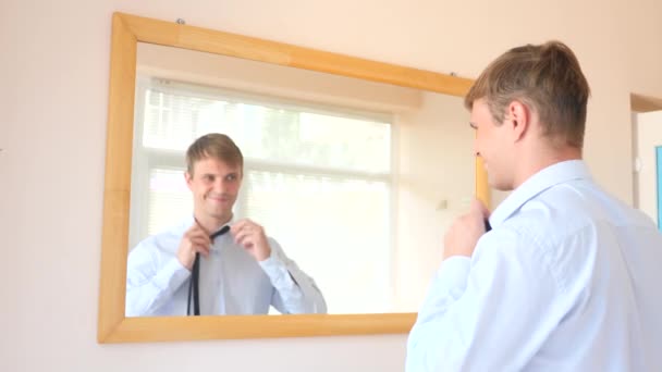 Le joyeux mec se déshabille devant le miroir et sourit à son reflet. 4k, au ralenti — Video