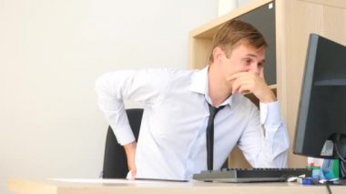 Genç bir adam, bir bilgisayarda çalışırken sırt ağrısı muzdarip. 4k, ağır çekim