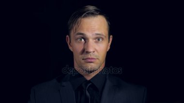 siyah bir arka plan üzerinde siyah giysili bir adam süper yakın çekim. 4 k. ağır çekim. başparmak adam ortaya çıktı. Süper oturum