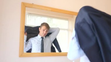 Neşeli bir sevimli adam gülümser ve bir ayna önünde onun yansıması Giydir. 4k, ağır çekim