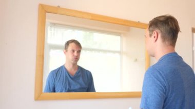 yorgun mutsuz adam bir ayna önünde undresses. 4k, ağır çekim