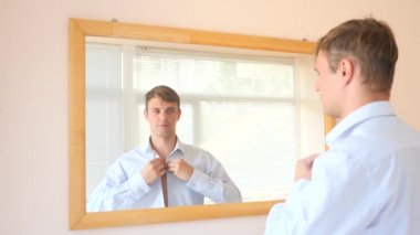 Neşeli bir sevimli adam gülümser ve bir ayna önünde onun yansıması Giydir. 4k, ağır çekim. bir gülümseme provası