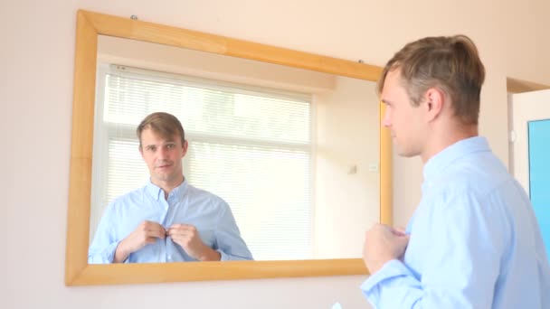 Zieht sich der fröhliche nette Kerl vor dem Spiegel aus und lächelt sein Spiegelbild an. 4k, Zeitlupe — Stockvideo