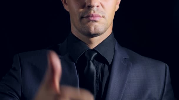 Super close-up van een man in de zwarte kleding op een zwarte achtergrond. 4 k. Slow-motion. man verschijnt duimen. super ondertekenen — Stockvideo