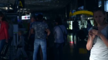Kadın bir smartphone Havaalanı lounge bekleyen kullanır. Havaalanında uçuş beklentilerini. 4k, ağır çekim