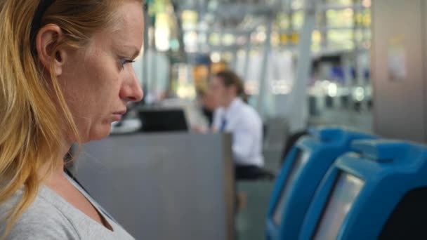 Mujer en la sala de espera del aeropuerto. Expectativas de vuelo en el aeropuerto. 4k, cámara lenta, la chica en el aeropuerto mira el tablero de información . — Vídeos de Stock