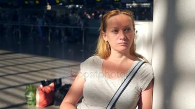 Kadın Havaalanı bekleme salonunda. Havaalanında uçuş beklentilerini. 4k, ağır çekim, bilgi yönetim kurulu Havaalanı bakar kıza.