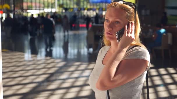 Kadın bir smartphone Havaalanı lounge bekleyen kullanır. Havaalanında uçuş beklentilerini. 4k, ağır çekim — Stok video