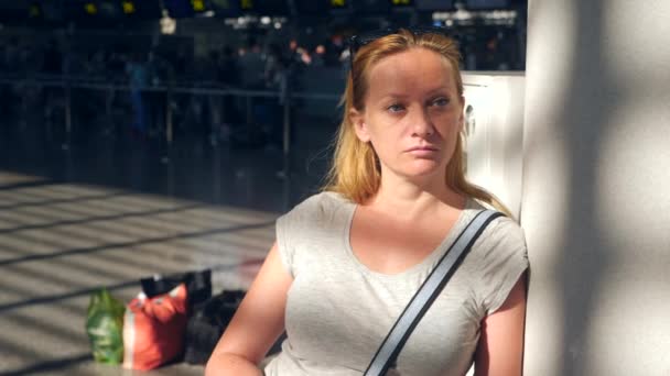 Donna in sala d'attesa all'aeroporto. Aspettative di volo in aeroporto. 4k, rallentatore, la ragazza all'aeroporto guarda il tabellone informativo . — Video Stock