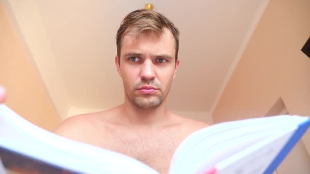 Homem lendo livro, deitado na cama em casa. 4k câmera lenta — Vídeo de Stock