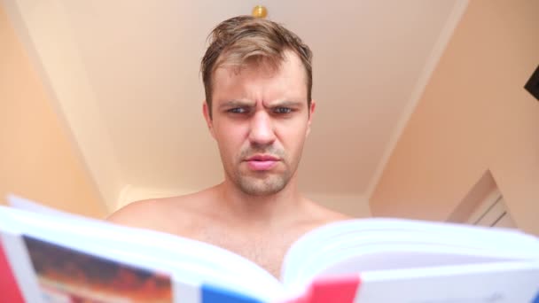 Hombre leyendo libro, acostado en la cama en casa. 4k cámara lenta — Vídeos de Stock