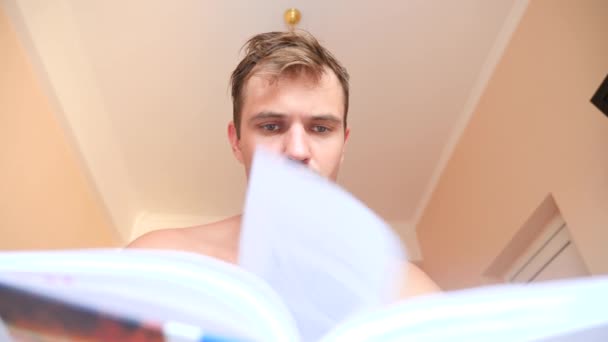 Mann liest Buch, liegt zu Hause im Bett. 4k Zeitlupe — Stockvideo