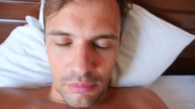 Bir yatakta yatarken aptal bir yüz buruşturma olan genç bir adam portresi. 4 k yavaş hareket
