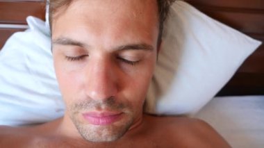 Bir yatakta yatarken aptal bir yüz buruşturma olan genç bir adam portresi. 4 k yavaş hareket