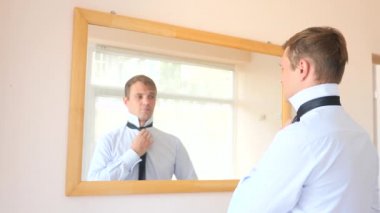 Neşeli bir sevimli adam gülümser ve bir ayna önünde onun yansıması Giydir. 4k, ağır çekim