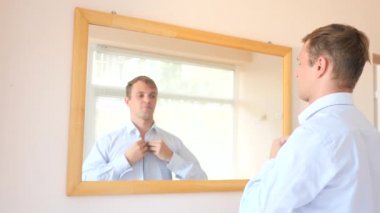 Neşeli bir sevimli adam gülümser ve bir ayna önünde onun yansıması Giydir. 4k, ağır çekim