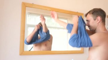 Neşeli bir sevimli adam gülümser ve bir ayna önünde onun yansıması Giydir. 4k, ağır çekim