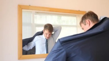 Neşeli bir sevimli adam gülümser ve bir ayna önünde onun yansıması Giydir. 4k, ağır çekim