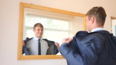 Neşeli iyi adam gülümsüyor ve ayna önünde onun yansıması undresses. 4k, ağır çekim