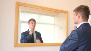 Neşeli bir sevimli adam gülümser ve bir ayna önünde onun yansıması Giydir. 4k, ağır çekim