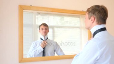 Neşeli bir sevimli adam gülümser ve bir ayna önünde onun yansıması Giydir. 4k, ağır çekim