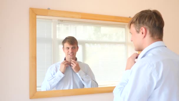 Ο εύθυμος συμπαθητικός τύπος γδύνεται μπροστά από τον καθρέφτη και χαμόγελα στο το είδωλό του. 4k, αργή κίνηση — Αρχείο Βίντεο