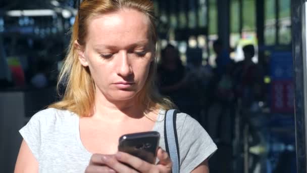 Frau benutzt Smartphone in Flughafen-Wartehalle. Flugerwartungen am Flughafen. 4k, Zeitlupe — Stockvideo