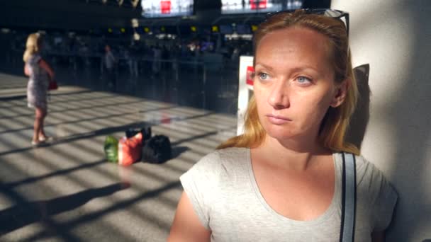 Kvinna i flygplats väntar lounge. Förväntningar på flyg på flygplatsen. 4k, ultrarapid, flickan på flygplats ser på informationstavlan. — Stockvideo