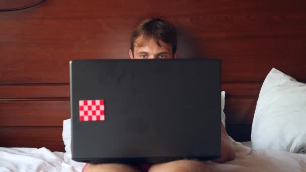 Mulher sexy tentando seduzir o homem trabalhando no laptop na cama. A rapariga tira a roupa interior à frente do namorado, e ele ignora-a, trabalha num portátil. 4k, câmera lenta — Vídeo de Stock